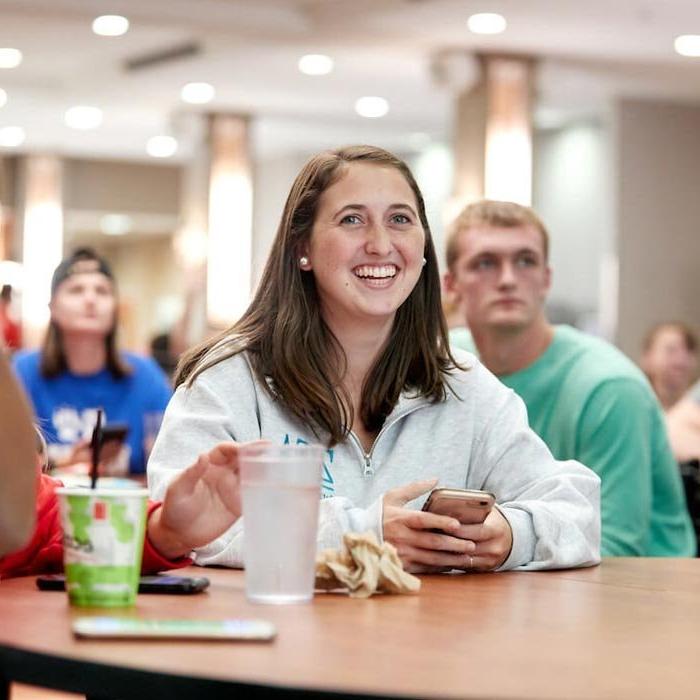 Student smiles while attending an event in the dining hall